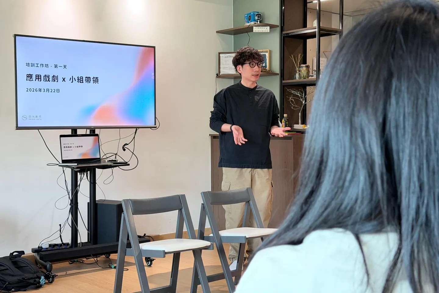 公開專業培訓中，謝偉倫站在屏幕旁講解應用戲劇與小組帶領